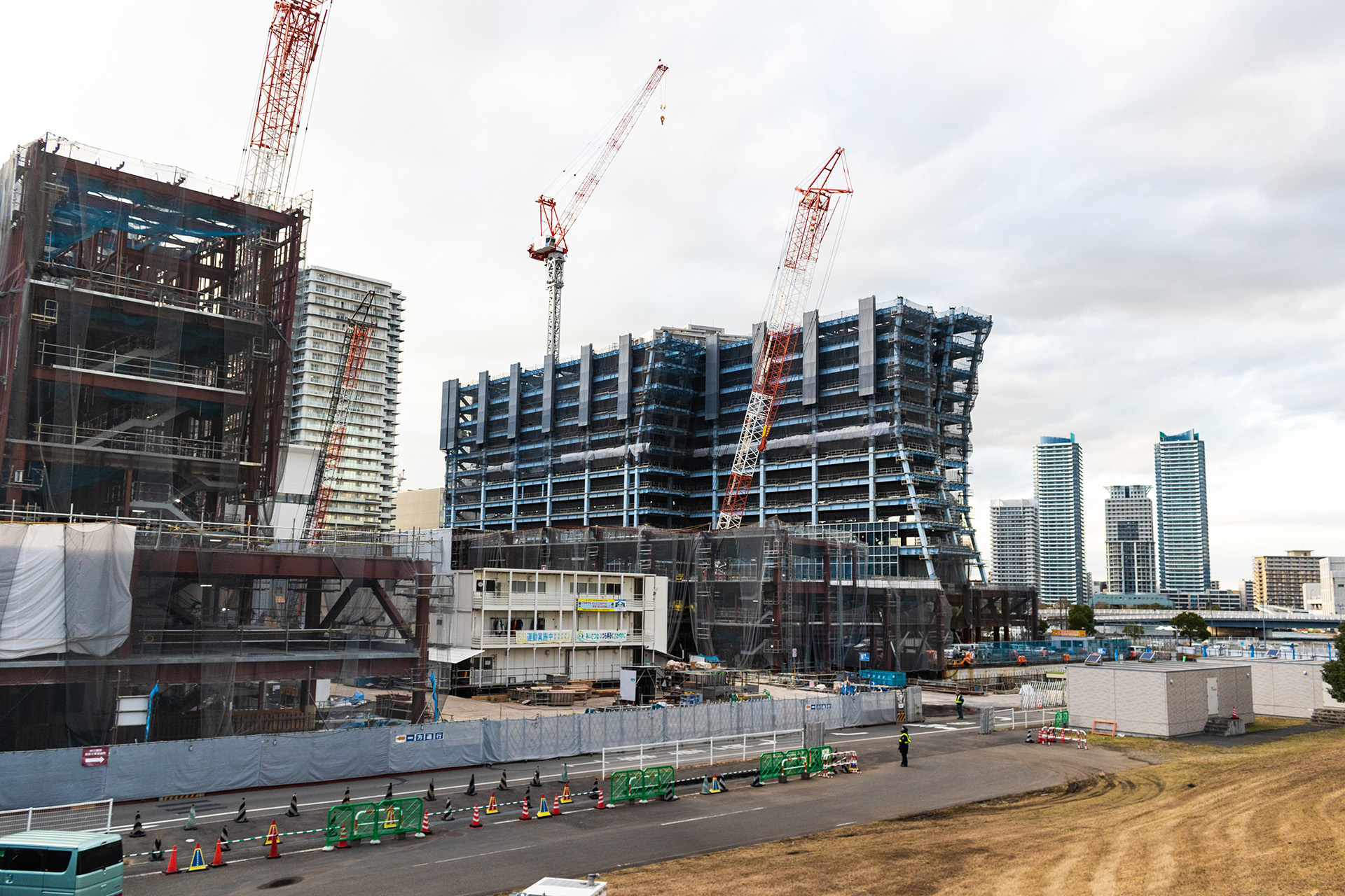 Construction site with cranes working on a work-in-progress wide multi-story building.